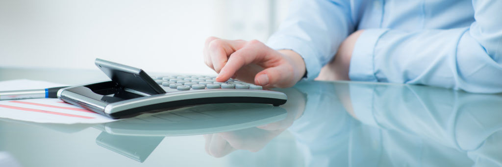 Hand typing buttons on calculator.