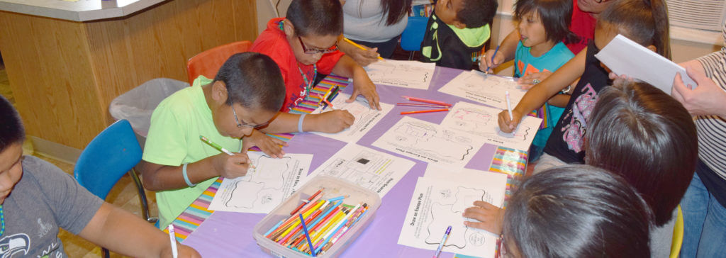Children at the Burns Paiute Tribe youth group sit at a table and complete an activity for Health Half Hour.