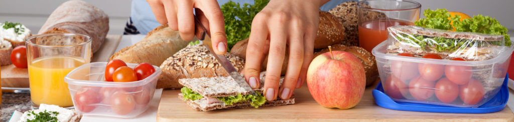 A person cutting a sandwich while making a healthy lunch
