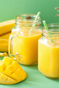 healthy yellow smoothie with mango pineapple banana in mason jars